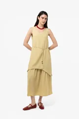 Vestido largo color mostaza, de silueta relajada, con escote en V, falda en capas y lazo fino regulable en la cintura.