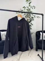 Canguro oversize negro con capucha y bolsillo tipo canguro. En la espalda presenta una estampa grande con diseño de mariposa, texto y la inscripción "top style" en color coral.
