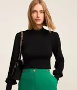 Suéter negro de punto con cuello alto, mangas largas abullonadas y puños largos.