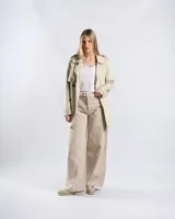 Campera trench de gabardina en color beige, con solapa cruzada, doble botonadura frontal, hombreras y cinturón ajustable para anudar en la cintura. Presenta bolsillos delanteros y puños ajustables con tiras.