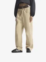 Pantalón de corte holgado color beige, con bolsillos delanteros y traseros. Presenta cintura elástica con cordón de ajuste y tres líneas verticales a los costados.