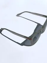 Lentes de sol Osten modelo Tokyo 2607 con armazón de acetato en tono gris translúcido y cristales oscuros. Presentan un detalle de línea roja en la patilla con el logo de la marca.