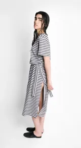 Vestido largo de corte recto, con cuello bote, mangas cortas y abertura lateral. Diseño a rayas horizontales en blanco y negro. Incluye lazo en la cintura.