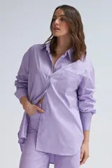 Camisa oversize color lavanda de poplin con cuello clásico, cierre frontal con botones, manga larga con puños abotonados y bolsillo de parche en el pecho.