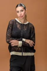 Campera tipo bomber confeccionada en encaje negro con detalles en color dorado en cuello, puños y ruedo. Presenta cierre frontal completo y diseño de mangas largas.