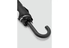 Paraguas plegable negro con estampado de lunares blancos y mango curvado de plástico negro.