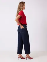 Jean wide leg de tiro alto, color azul oscuro, con pierna ancha, pretina con pasadores, botón y cierre. Cuenta con bolsillos delanteros y traseros.