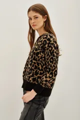Sweater de punto con estampado animal print en tonos negro y tostado, de cuello redondo y mangas largas con puños acanalados.