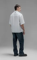 Camisa de manga corta con cuello cubano, corte oversize y cierre frontal de botones. Confeccionada en tejido de lyocell, presenta un diseño minimalista y liso.