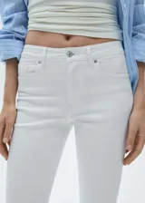 Jeans tiro medio de corte flare con diseño de campana y bajo deshilachado, con cierre de cremallera y botón, trabillas y cinco bolsillos.