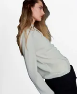 Blusa de poliéster color blanco con cuello redondo drapeado y mangas largas.