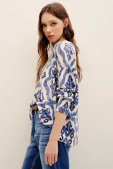 Sweater de punto color crudo con estampado geométrico en tonos azules, cuello redondo y mangas largas.