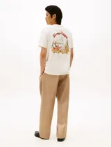 Remera de cuello redondo y manga corta, confeccionada en algodón regenerativo. Presenta un diseño minimalista en color blanco con el logo de la marca bordado en el pecho en tonos cálidos.