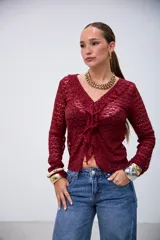 Blusa de encaje color bordó, de manga larga, con escote en V y volados en el borde delantero.