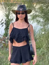 Top corto de tirantes finos en color blanco, con diseño de capas con terminación en punta y textura delicada en relieve.