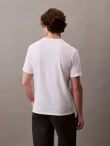 Remera de manga corta color blanco, con cuello redondo y corte regular. Presenta un estampado frontal con el logo y la inscripción 'Calvin Klein New York' en color bordó.