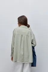 Camisa de manga larga con diseño de rayas verticales blancas y verdes, calce relajado, cuello clásico y botonadura frontal con botones perlados.