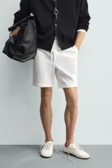 Bermuda regular fit de tejido elástico color blanco, con cintura elástica ajustable mediante cordón, bolsillos delanteros y bolsillos traseros de vivo.