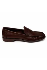 Mocasín de símil cuero color marrón, con diseño clásico, costuras marcadas en el empeine y suela plana con taco bajo.