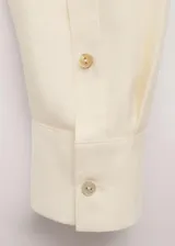 Camisa de seda 100% color marfil, de corte recto, con cuello camisero clásico y cierre frontal de botones ocultos.