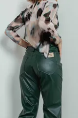 Pantalón de cuero sintético verde con corte recto, tiro alto y botones metálicos a lo largo de la pierna.