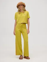 Pantalón de punto color verde oliva, confeccionado en algodón, con corte holgado, pierna ancha y tiro alto. Cuenta con pretina elástica con cordón de ajuste y una línea lateral a contratono en color naranja.