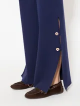 Pantalón azul de hilado frío, tejido cerrado y pesado, largo a los tobillos, con botones dorados en los laterales.