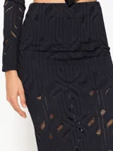 Pollera tubo negra confeccionada en tela de punto calada, con cintura elastizada, calce ajustado y pollera corta interna.