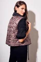 Chaleco negro con cierre frontal y cuello alto, de corte al cuerpo y diseño acolchado. Reversible, con interior a cuadros.