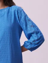 Blusa amarilla texturada con escote redondo y mangas 3/4 con puño elastizado. Aplique de broderie en escote y mangas. Marca Ruby Rd.
