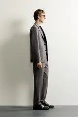 Pantalón de vestir regular fit color gris con sutil patrón a cuadros, confeccionado con mezcla de lana. Cuenta con bolsillos frontales, bolsillos traseros de doble vivo con botón, trabillas para cinturón y raya marcada en las piernas.