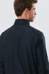 Campera liviana de nylon color azul marino, con cuello alto, cierre frontal y puños y dobladillo en elástico tejido.