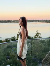 Blusa tipo lencera de satén color crema con escote en V y ruedo asimétrico, ambos decorados con encaje negro. Presenta breteles finos ajustables.