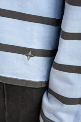 Sweater tipo polo de manga larga con diseño de rayas horizontales en tonos celeste y marrón oscuro. Presenta cuello camisero con abertura frontal y corte recto.