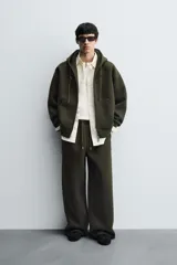 Pantalón de corte wide fit confeccionado en tejido técnico con efecto neopreno. Presenta cintura elástica ajustable con cordón, perneras anchas con costura frontal, bolsillos laterales y bolsillos traseros de plastrón.