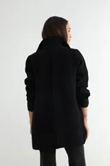 Abrigo de paño negro con cuello camisero, cierre frontal de botones, bolsillos laterales de parche y mangas largas con detalle de botón en los puños.