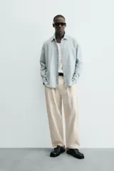 Camisa de denim de algodón, color celeste claro lavado, de corte relajado (relaxed fit) con cuello solapa, manga larga terminada en puño con botón y cierre frontal de botonadura. Presenta un pequeño bordado a contraste en el pecho.