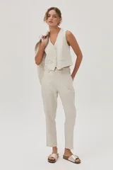 Pantalón chino de lino metalizado color beige, tiro medio-alto y pierna recta. Cuenta con bolsillos laterales y traseros.