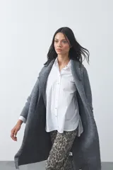 Cardigan de tejido de punto gris, con silueta larga, frente abierto, solapas clásicas y bolsillos aplicados en los laterales.