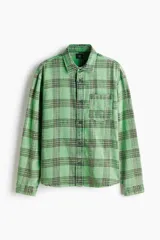 Camisa H&M de sarga de algodón verde con diseño de cuadros oscuros, cuello inglés, un bolsillo en el pecho y cierre frontal de botones.