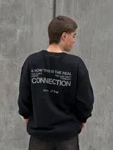 Buzo negro de corte holgado con cuello redondo y puños acanalados. Estampado frontal con la palabra "OSTEN" y la frase "NOT WHERE YOU'RE FROM A MINDSET OF BECOMING" en color blanco.