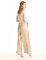 Pantalón wide leg de tela laminada metalizada color blanco, con pretina elástica y lazo de ajuste en la cintura. Cuenta con bolsillos laterales.