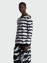 Buzo de punto con rayas horizontales blancas y negras, con texto manuscrito en negro y botones dorados en el hombro.