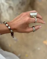Pulsera artesanal compuesta por una serie de cuentas metálicas irregulares ensartadas en un hilo de algodón natural. Diseño rústico y minimalista.