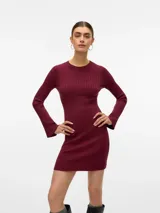 Vestido corto de tejido de punto acanalado en color bordó, con cuello redondo y mangas largas con terminación ligeramente acampanada. Presenta un diseño ajustado al cuerpo.