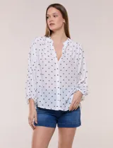 Blusa holgada de gasa texturizada color blanco con estampado de lunares negros, escote en V con botones frontales, mangas 3/4 abullonadas y puños elásticos.