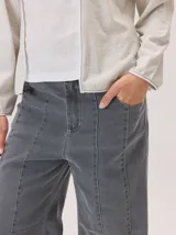 Pantalon de corte recto con costuras verticales decorativas en contraste color rojo. Presenta cintura con trabillas, cierre frontal con botón y bolsillos laterales.