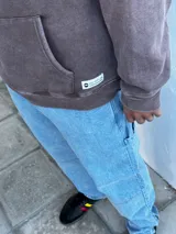 Jean azul claro de corte amplio, estilo carpintero, con pespuntes en contraste y cierre en el tobillo.