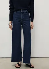 Jeans de tiro alto con corte culotte y pernera ancha. Presentan un diseño de cinco bolsillos, cierre frontal con cremallera y botón, y bajo con acabado deshilachado.