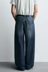 Jeans de denim de algodón, color azul oscuro con efecto lavado. Presentan un corte muy holgado (baggy fit) en toda la pierna y tiro medio. Tienen cinco bolsillos y cierre frontal con cremallera y botón.